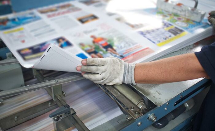 A printer wearing gloves looking over a printed layout for accuracy.